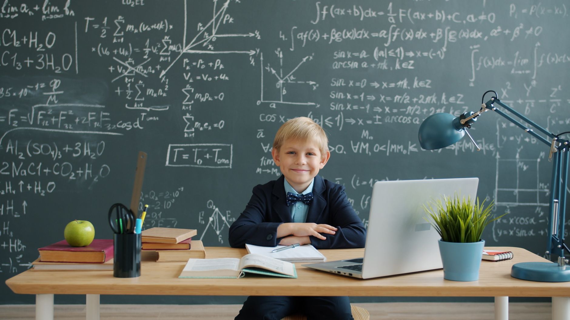photographic | high school student solving chemistry equations on laptop with periodic table on desk